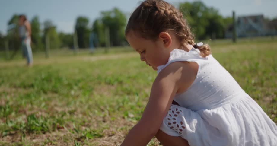 A little girl picks a flower and smells it