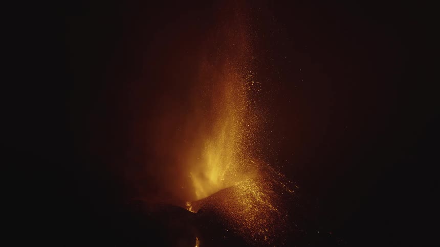 An erupting volcano spraying bright lava upwards on a night
