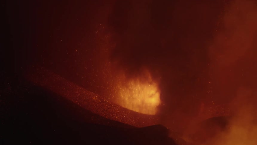 A volcano is erupting and releasing larvae and smoke upwards and are glowing orange