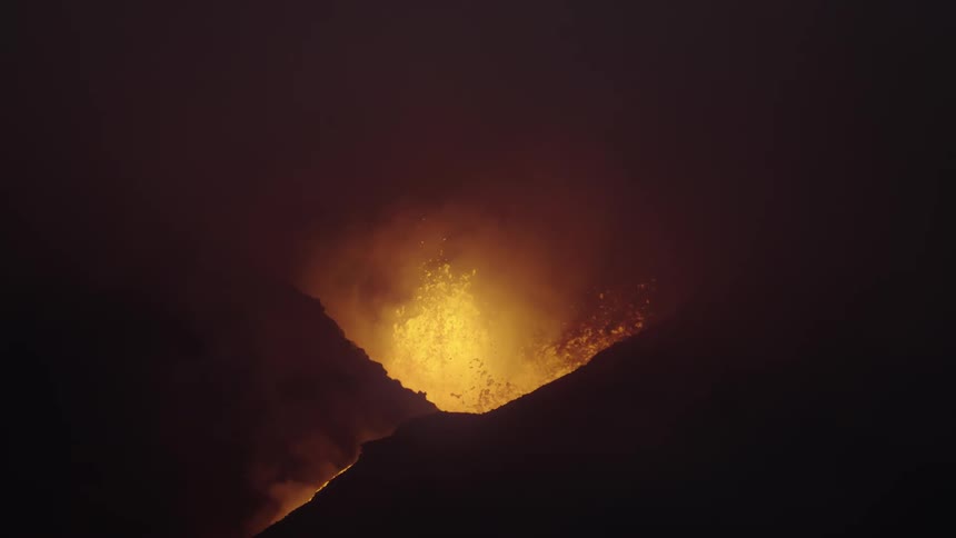 Orange volcano lava flame fountain shooting up from mountain at night