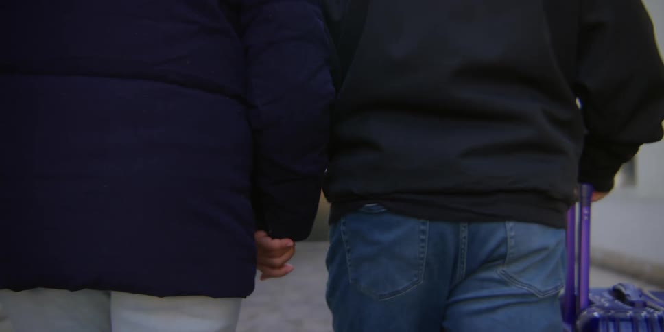 Two people hold hands while walking