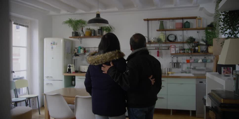 A couple is admiring a modern and bright kitchen from a living room