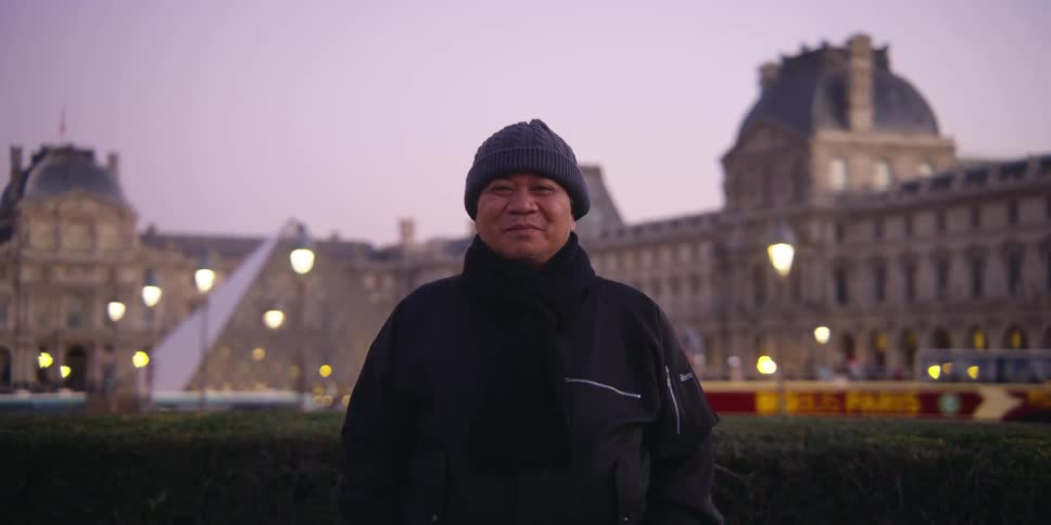 A portrait of a man in front of a large building in a city