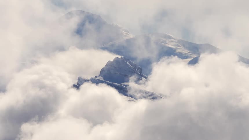 A towering mountain range is shrouded in a dense layer of clouds