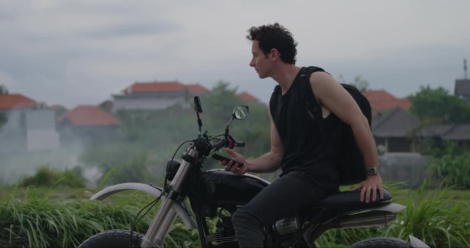 A white male sitting on a motorcycle uses a smart phone