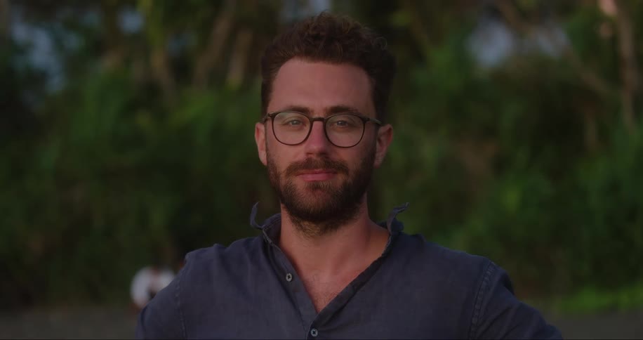Close up of a bearded man wearing glasses standing outdoors