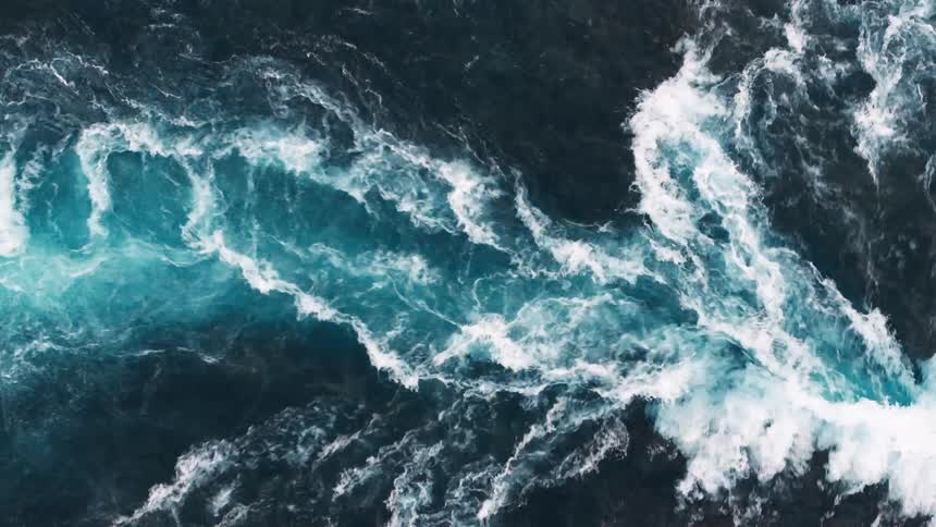 A top view of a river with turbulent waves and white foam