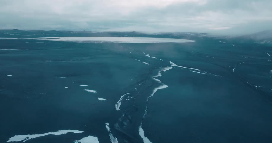 White ice sheets against dark gray under a cloudy sky