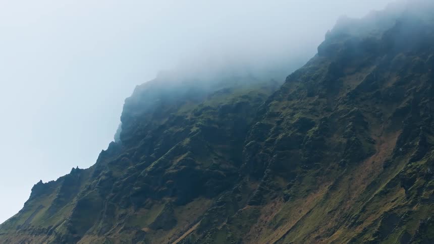 A rugged mountain landscape partially obscured by clouds