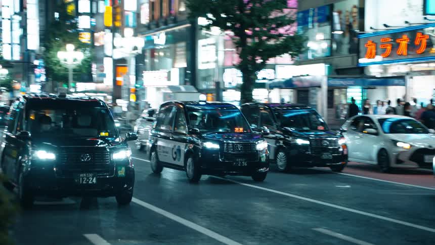 A nighttime city scene with taxis and illuminated signs