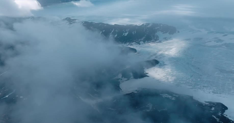 Aerial panorama of a day with lots of clouds overlooking mountains covered in snow