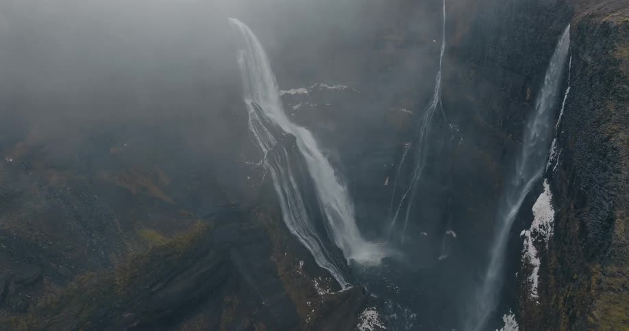 Aerial view of a powerful waterfall in the misty mountains