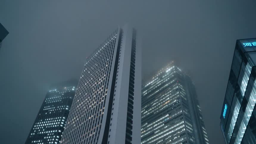 A misty cityscape with illuminated buildings at night