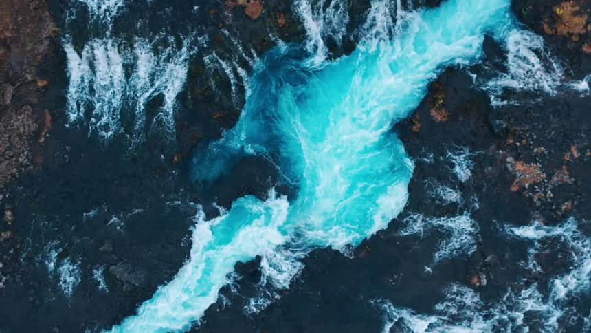 Aerial of a river with blue waters over a volcanic rock