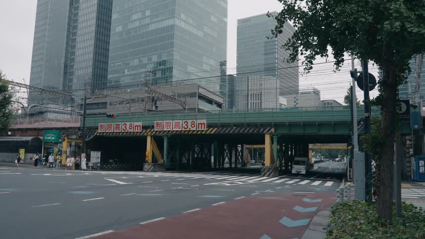 People wait to cross the street as vehicles travel beneath an overpass