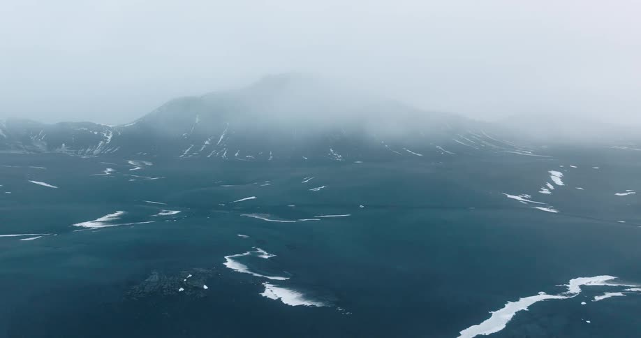 A large plain with pools of water or ice surround a mountain