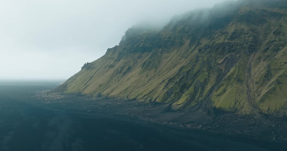 Aerial view of misty mountains surrounded by a dark terrain