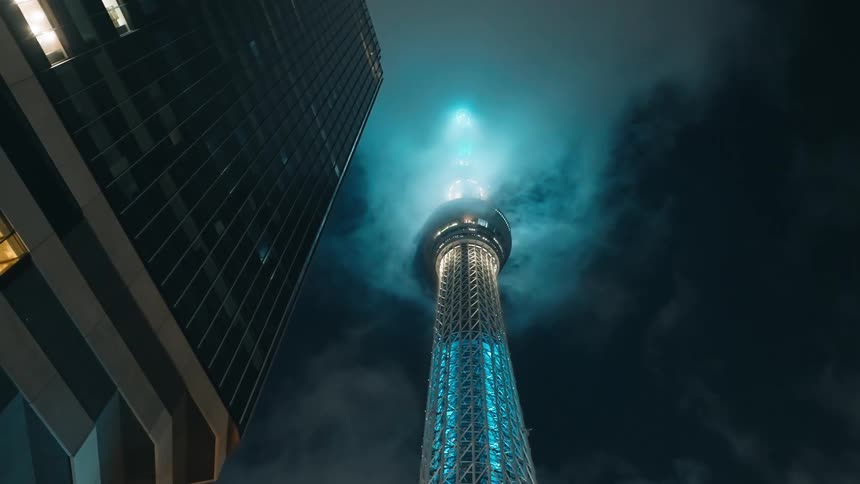 A glass tower with a bright blue light in the city