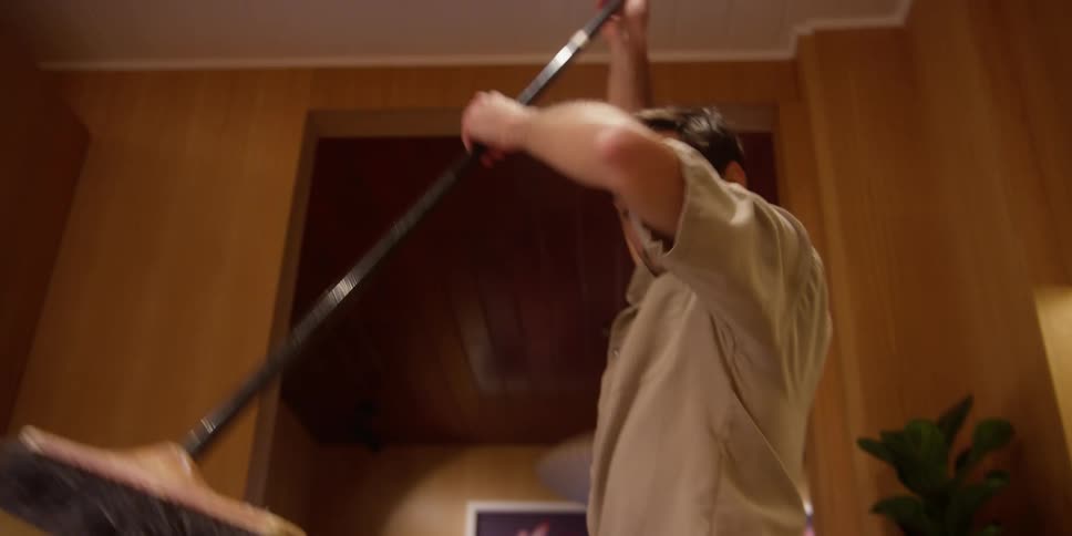 A man cleaning the kitchen floor with a mop