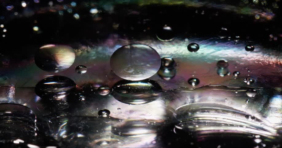 Extreme closeup on a transparent and shiny liquid in abstract movement and slow motion
