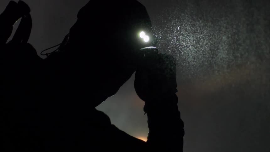 A man in the middle of a mountain at night on a rainy and snowy day