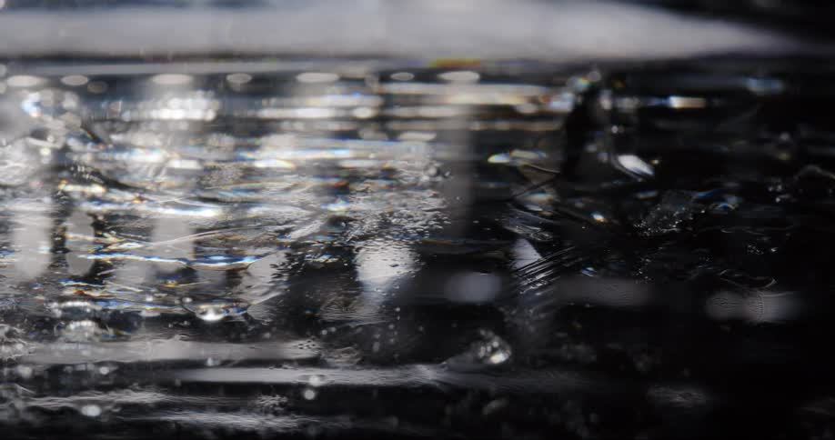 Droplets and ripples on a dark reflective liquid surface