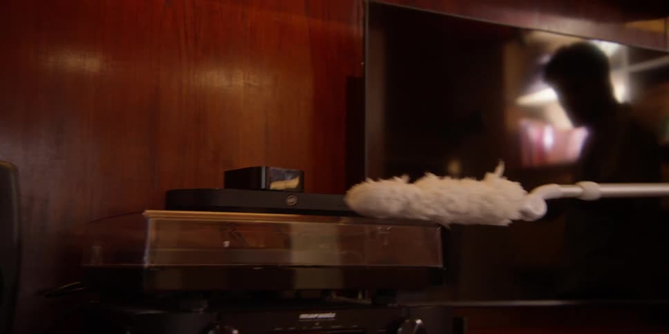 A man jerks his body about while dusting