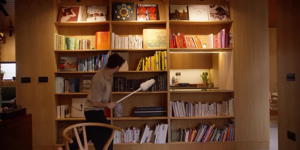 A man cleaning the bookshelf while dancing