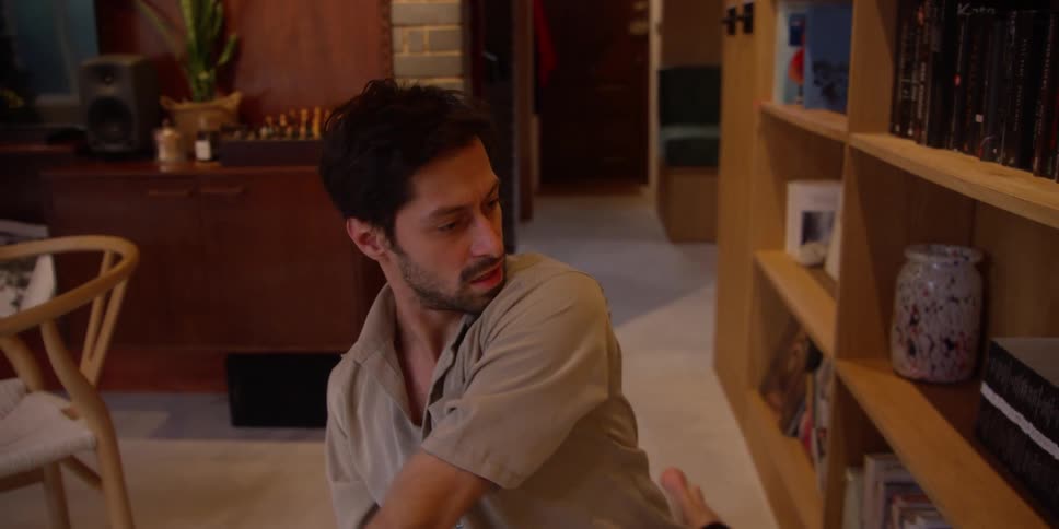A man dances while touching books on a shelf