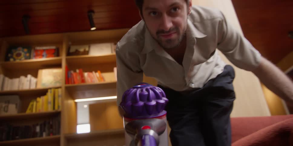 Closeup of a mans face vacuuming the living room floor