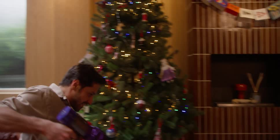 A man dances dramatically while vacuuming a living room