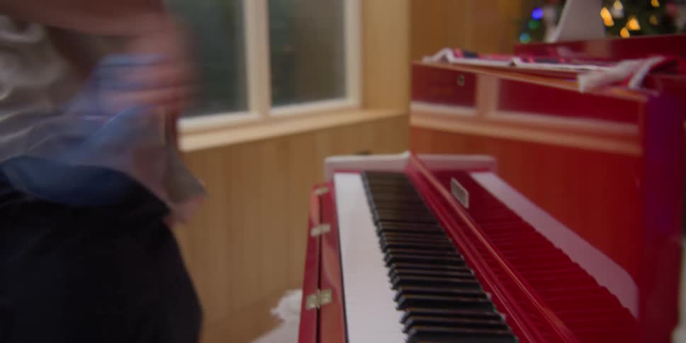 A man dusts a piano while dancing around
