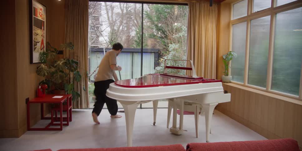 Man dances while sweeping around piano