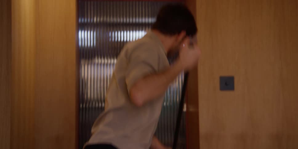 A man dancing with a broom at home