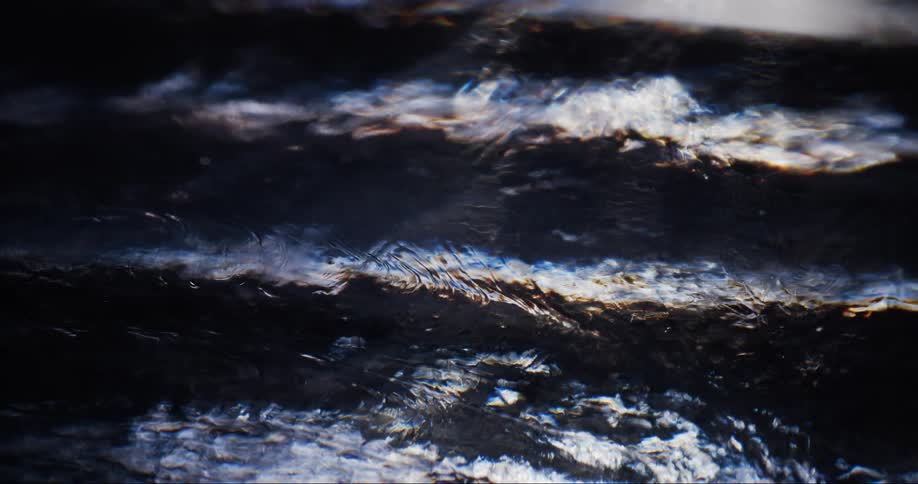 A liquid moving in a dark texture below