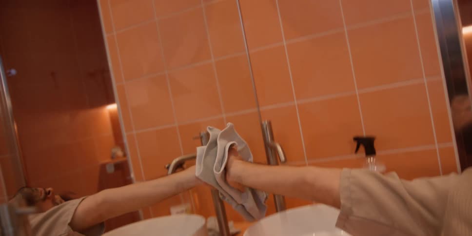 A young man dances while cleaning the bathroom mirror