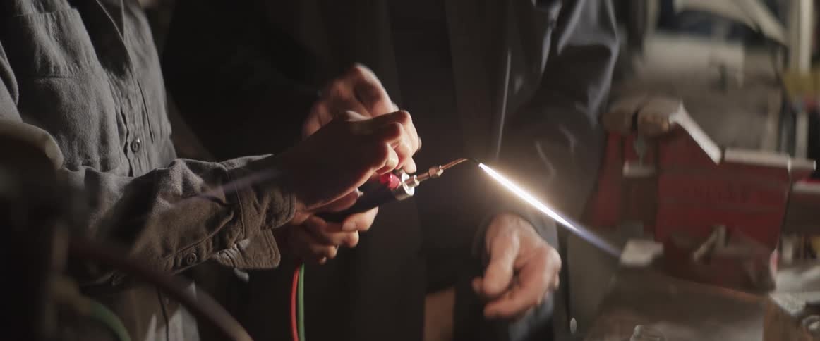 A man shows a woman how to light a torch