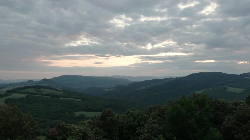 High clouds are hovering over hills at dusk or dawn