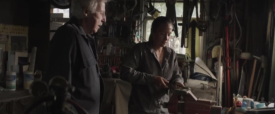 Elderly man and a young woman indoors performing manual movements on a machine