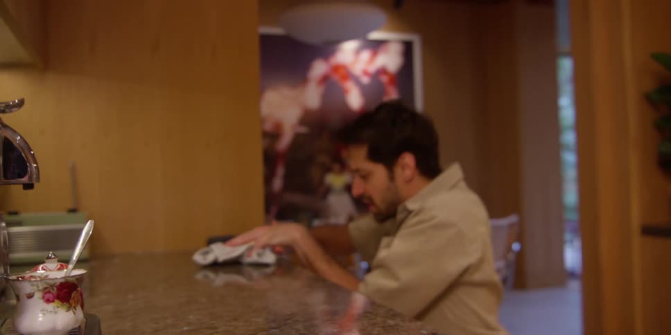 A man dances while cleaning the kitchen counter