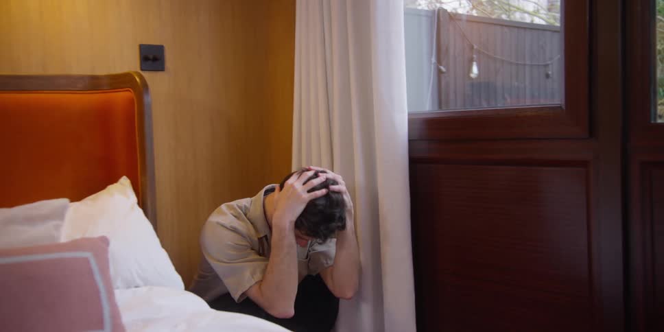 A man does a front flip by his bed
