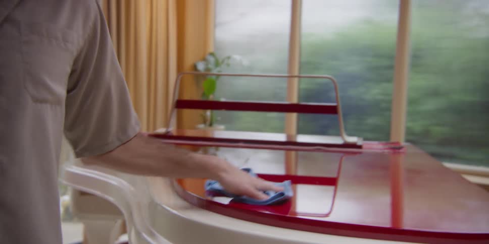 A man dances while wiping down a piano
