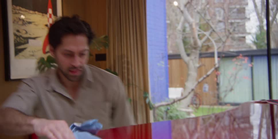 A man doing dance moves while polishing a table surface