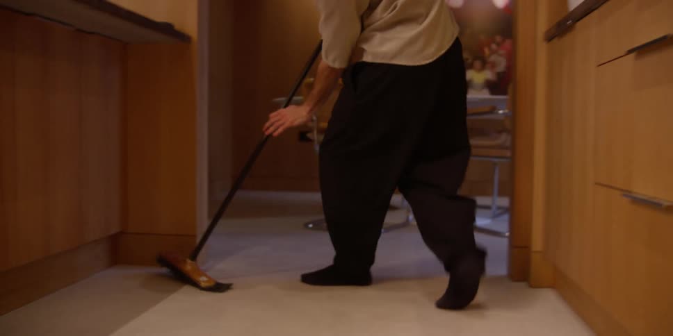 A person cleaning a white floor using a broom