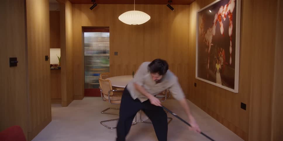 A man dances while sweeping the room