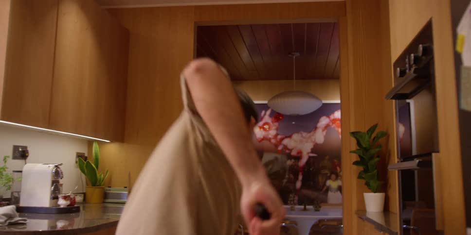 A man dances while cleaning a kitchen with a broom