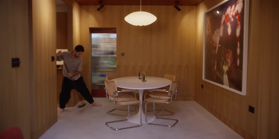 A man dances while sweeping the dining room floor