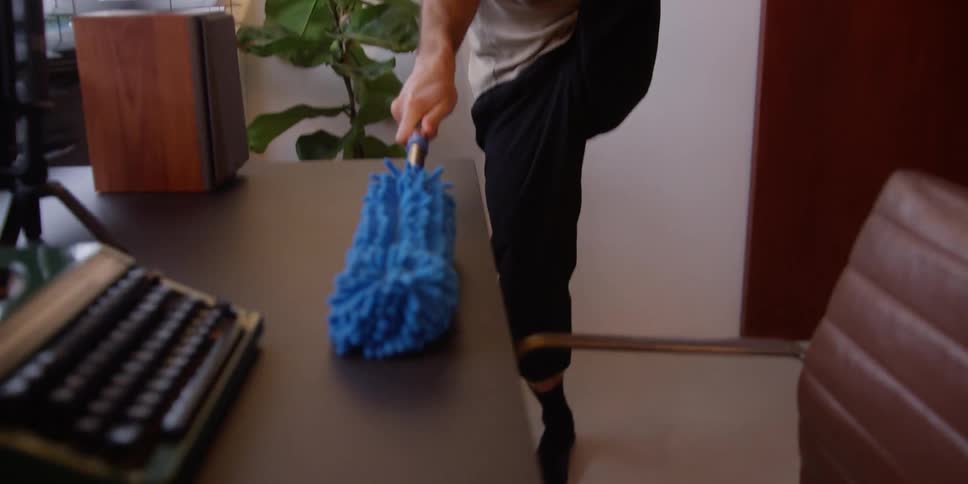 A man doing dance moves while cleaning a table and arranging objects