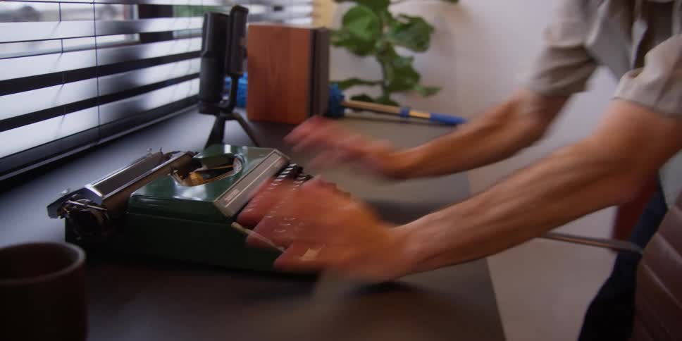 A man meticulously arranges an office desk while dancing