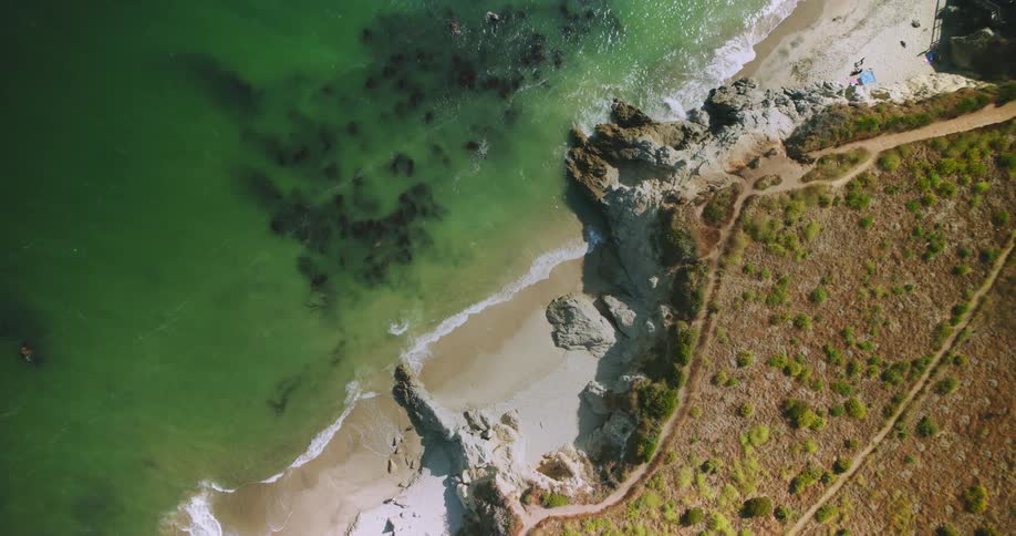 A coast of a beach with small waves breaking on the sand and the sea is green